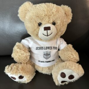 A teddy bear with jesus loves you on it