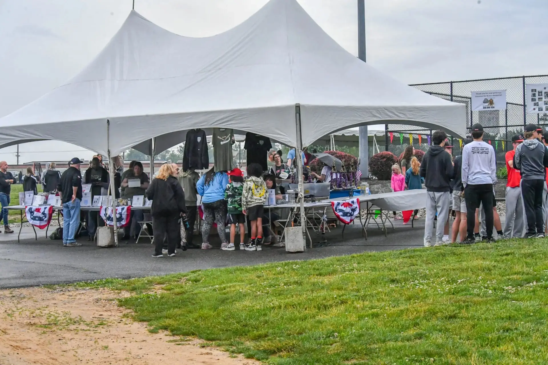 Outdoor event with people under white tent.